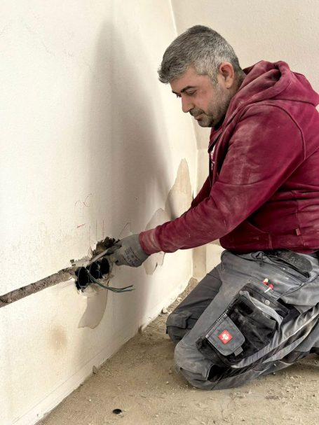 Elektriker arbeitet an einer Elektroinstallation in einer Innenwand in Konstanz.