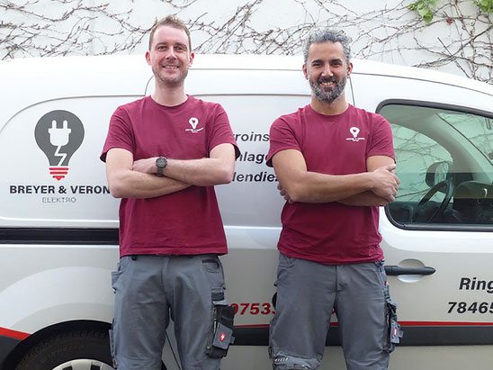 Die Geschäftsführer von Elektro  Breyer & Veron stehen vor einem Firmenfahrzeug in Konstanz.