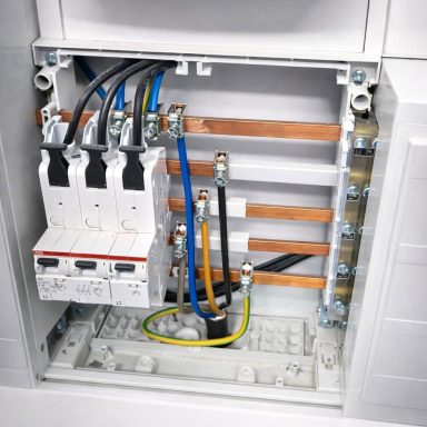 Geöffneter Verteilerkasten mit installierten Leitungen und Sicherungskomponenten.