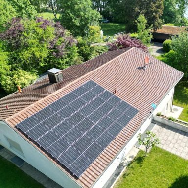 Photovoltaikanlage auf einem Wohnhaus mit rotem Ziegeldach und Garten in Konstanz.