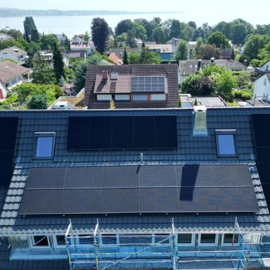 Photovoltaikanlage mit schwarzen Solarmodulen auf einem Wohnhausdach mit Blick auf den Bodensee in Konstanz.